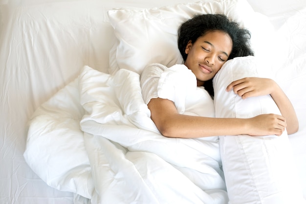 American cute girl sleep with happy dream on white bed 