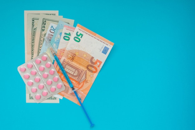 American dollar and euro banknotes. medical mask, vaccine syringe and pink pills, pills blister. Economy crisis. Health expense. Outbreak of coronavirus.