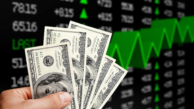 Фото Американский доллар в руке человека и экран фондового рынка, фон денежного графика