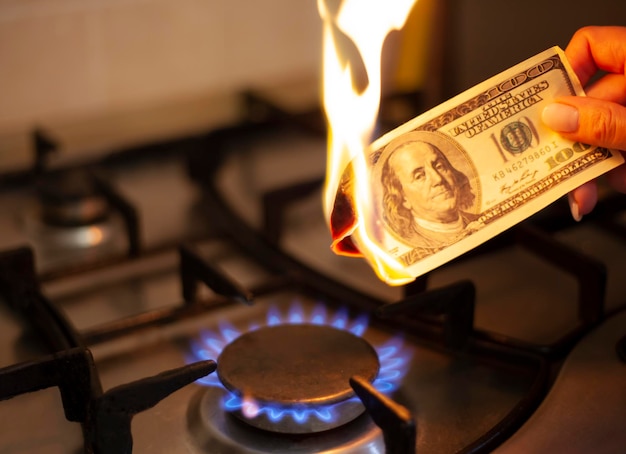 The american dollar is burning in the fire Burning gas burner on the background of one hundred dollars The concept the rise in the price of gas in USA Expensive gas supply