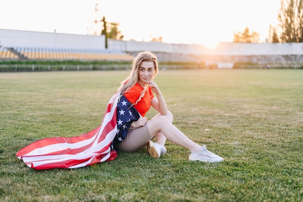 American Flag Girl at Sunset Girl with Flag Sits on Green Grass