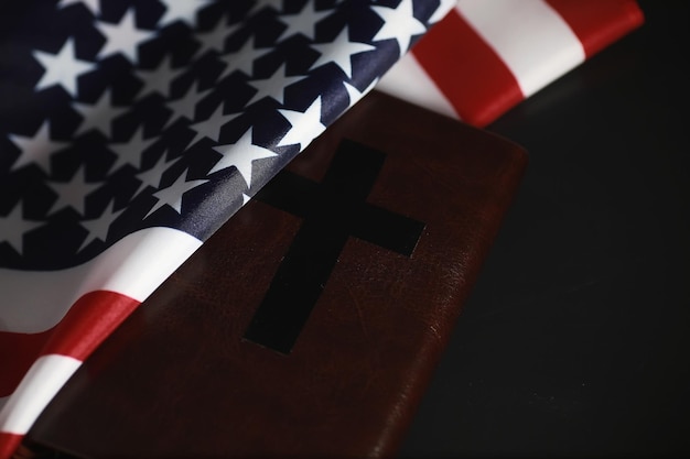 American flag and holy bible book on a mirror background Symbol of the United States and religion Bible and striped flag on a black background