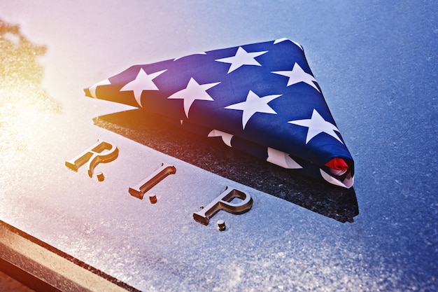 Американский флаг на мемориальной мраморной гробнице с RIP