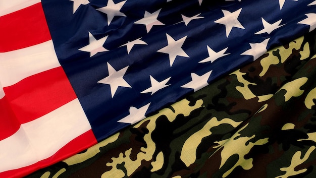 アメリカの国旗とミリタリー迷彩パターン。上面図の角度。白い背景の上のアメリカ国旗と兵士の旗。カモフラージュ生地とアメリカの国旗でミリタリーコンセプトを表現。