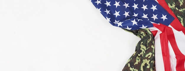 Foto bandiera americana e motivo mimetico militare. angolo di visione dall'alto. bandiera del soldato con la bandiera americana nazionale su sfondo bianco. rappresenta il concetto militare con il tessuto mimetico e la bandiera nazionale degli stati uniti.