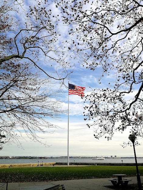 American flag at river against cloudy sky