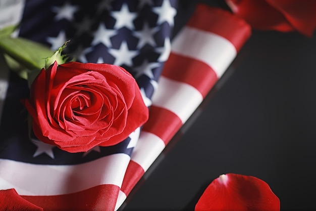 Американский флаг и цветок розы на столе. Символ Соединенных Штатов Америки и красных лепестков. Патриотизм и память.
