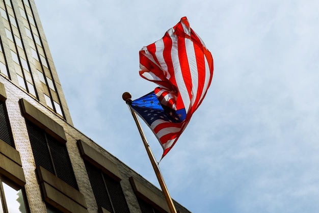 An american flag waving against two skyscrapers and a blue sky