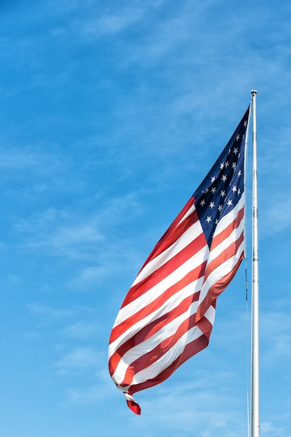 American flag waving on blue sky background in Key West, USA on sunny day. National symbol, citizenship and patriotism concept. Pride, freedom and unity.