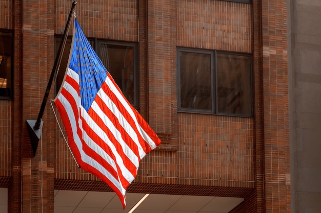 Bandiera americana che ondeggia sulla costruzione con i grattacieli new york stati uniti