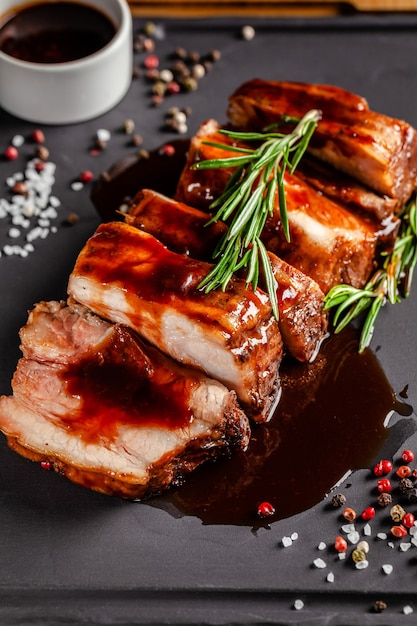 Foto concetto di cibo americano. costine di maiale alla griglia con salsa alla griglia, con fumo, spezie e rosmarino. immagine di sfondo. copia spazio