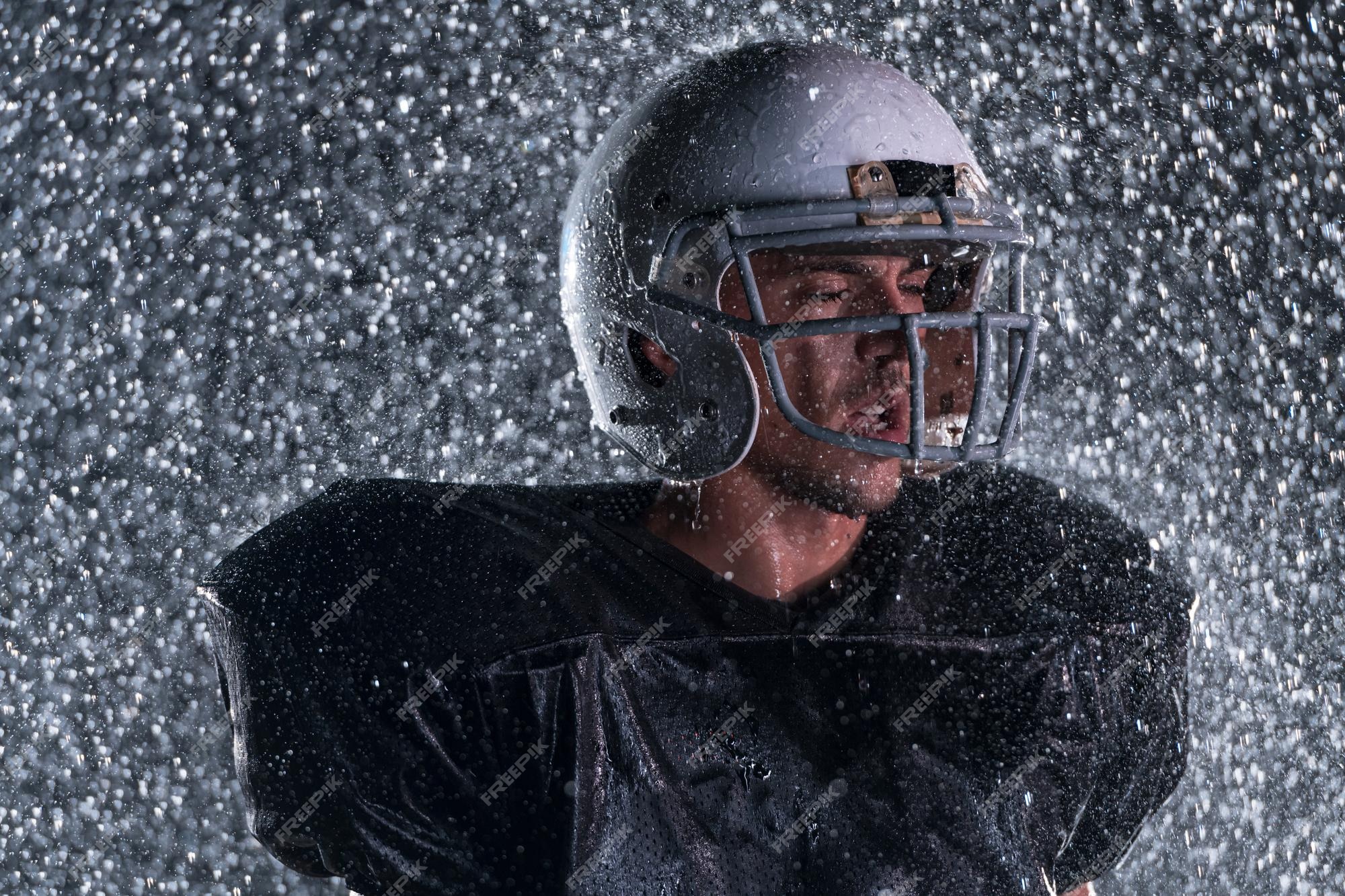 Premium Photo  American football athlete warrior standing on a field holds  his helmet and ready to play. player preparing to run, attack and score  touchdown. rainy night with dramatic lens flare