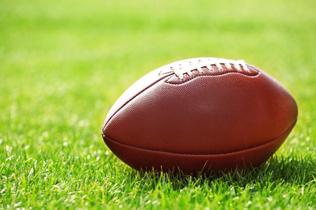 American football ball on a green grass