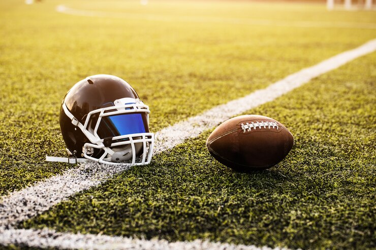 American Football Helmet and ball on green grass