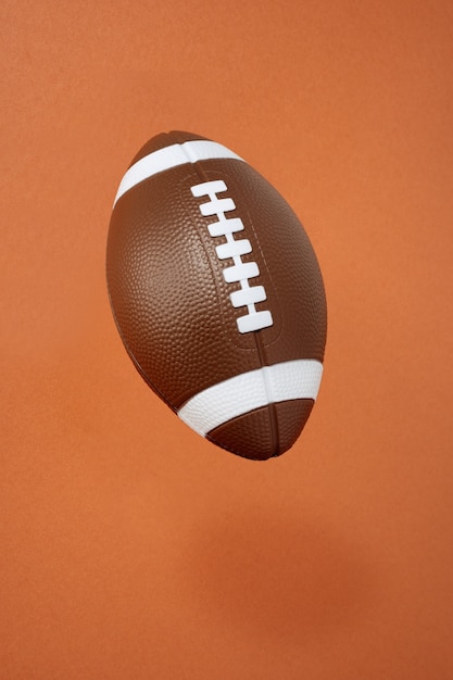 Football americano su sfondo arancione. sport e competizione. copia spazio. illustrazione 3d