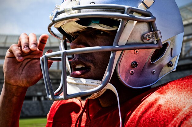 American football player against rugby stadium on a sunny\
day