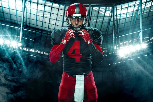 American football player athlete sportsman in red helmet on dark background with smoke sport and