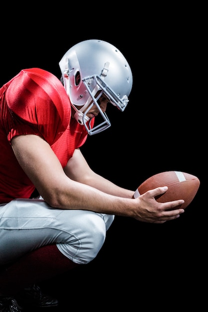 American football player crouching while holding ball