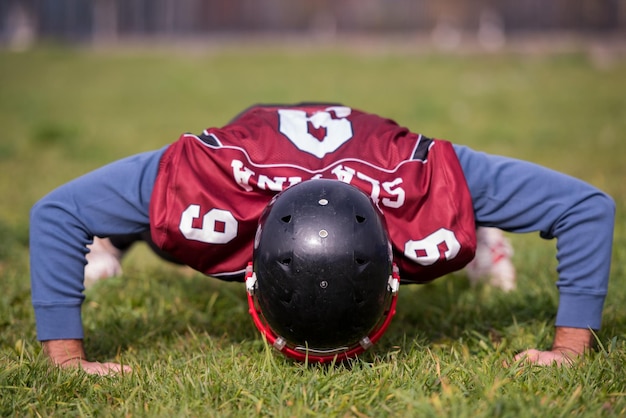 Foto giocatore di football americano che fa flessioni durante l'allenamento sul campo