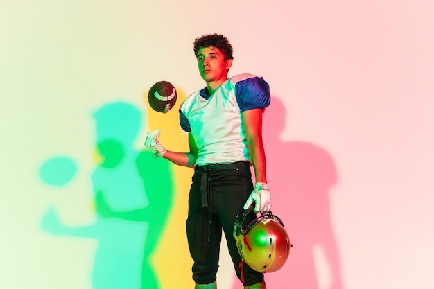 American football player on gradient studio background in neon