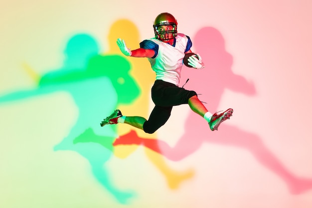 American football player on gradient studio background in neon