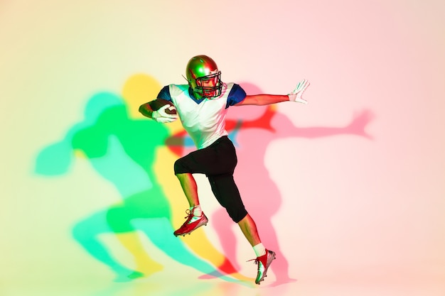 Photo american football player on gradient studio background in neon