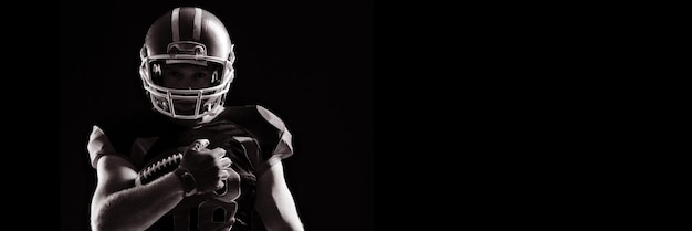 American football player in helmet holding rugby ball