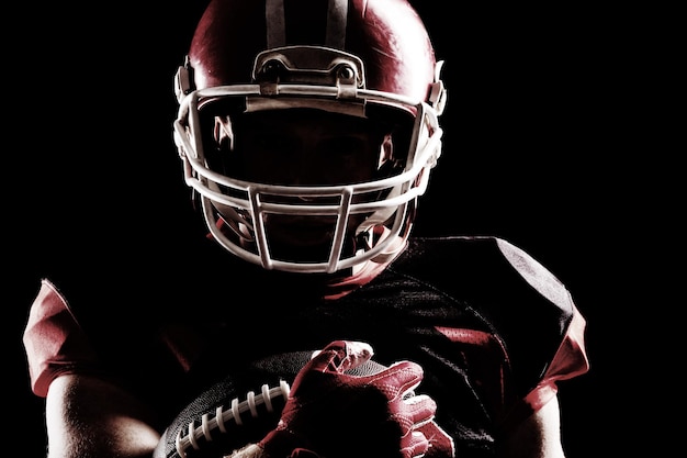 American football player in helmet holding rugby ball