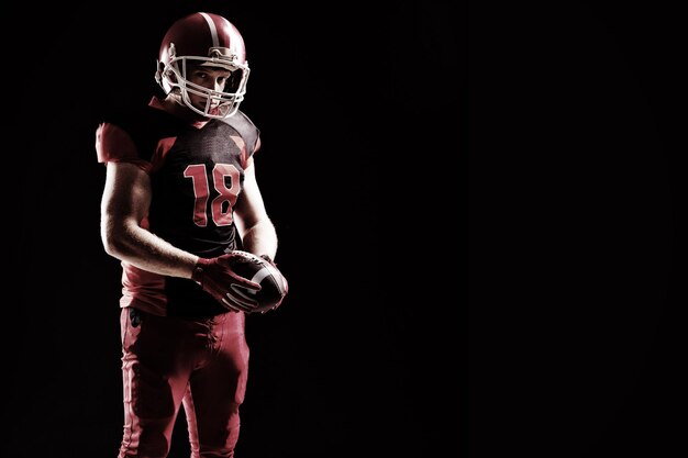 Photo american football player in helmet holding rugby ball