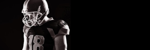 American football player in helmet standing against black background