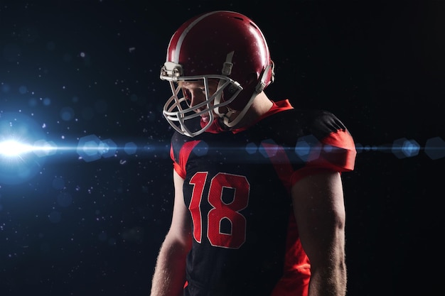 American football player in helmet standing against black background