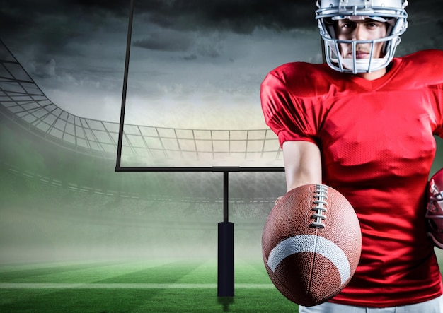 American football player holding rugby ball against stadium in background