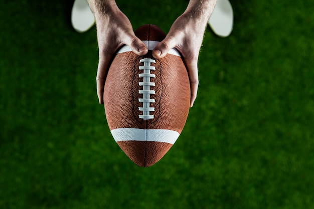 Photo american football player holding up football
