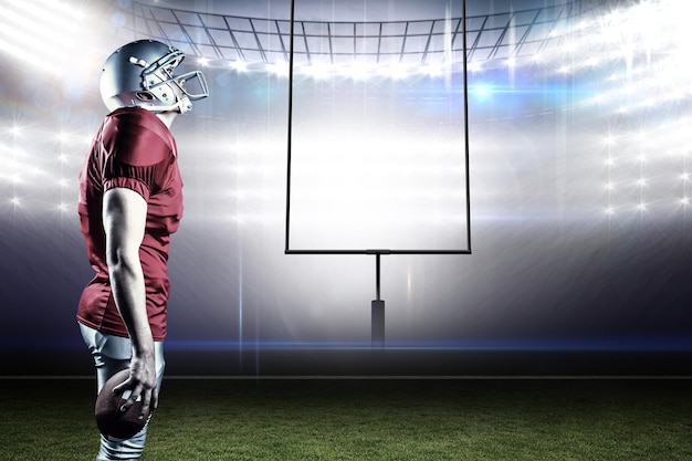 Photo american football player looking up while standing against american football arena