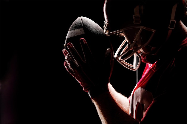 Foto giocatore di football americano in piedi con casco e palla da rugby