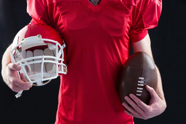 An american football player taking a helmet and ball in her hands 