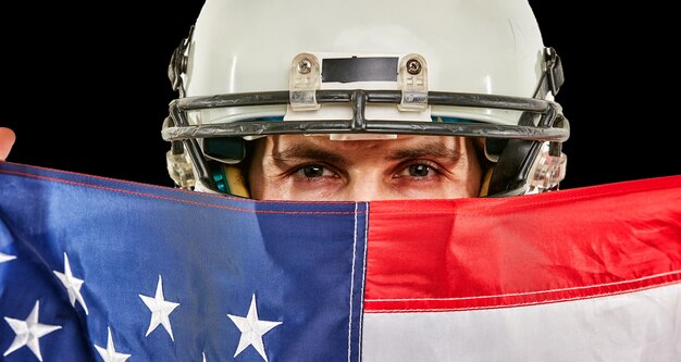 Foto giocatore di football americano con uniforme e bandiera americana orgoglioso del suo paese, su uno spazio bianco.