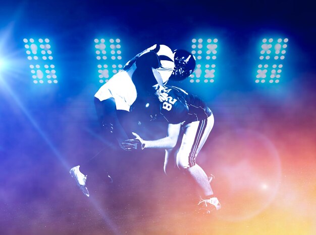 Photo american football players in action at night game time on the field