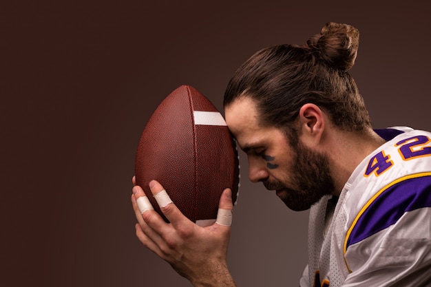 American football-speler met een bal op het moment om te bidden voor de wedstrijd