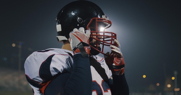 American football-speler zet zijn beschermende helm op tegen felle stadionverlichting