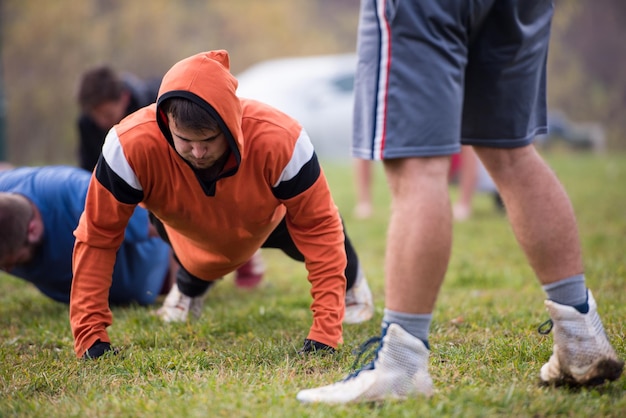 Foto squadra di football americano che fa flessioni durante l'allenamento sul campo