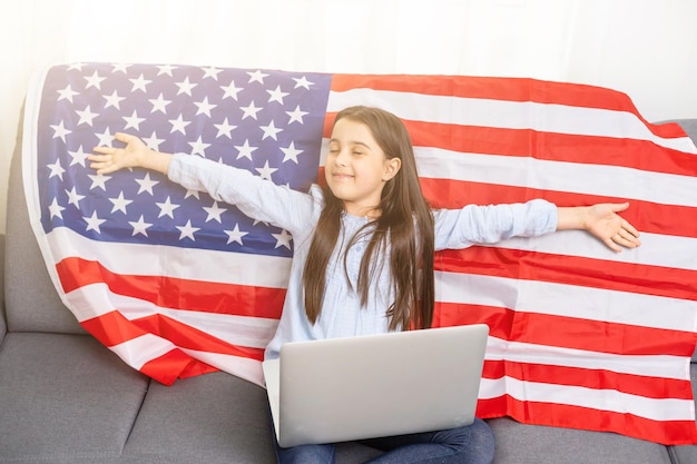 アメリカ人の女の子はオンラインニュースに見えます。ニュース。国旗制定記念日。アメリカ独立記念日。