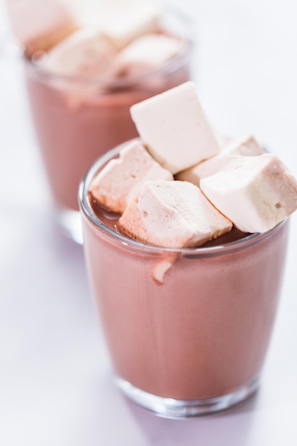 American hot chocolate topped with large marshmallow in glass cup.