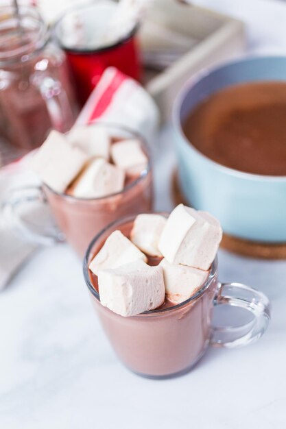 American hot chocolate topped with large marshmallow in glass cup.