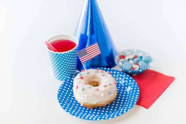 american independence day, celebration, patriotism and holidays concept - close up of glazed sweet donut with juice and candies in disposable tableware at 4th july party from top