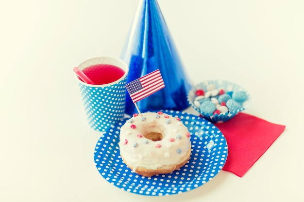 День независимости США, праздник, патриотизм и концепция праздников - крупный план глазированного сладкого пончика с соком и конфетами в одноразовой посуде на вечеринке 4 июля сверху