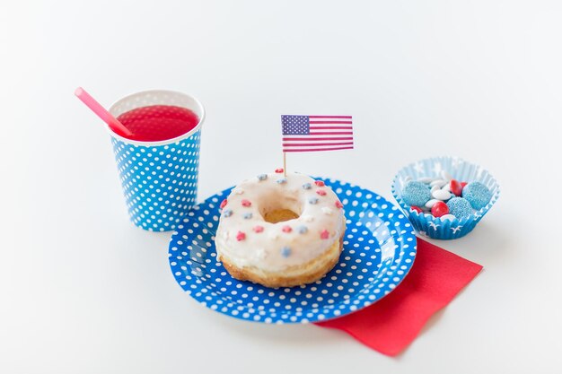 american independence day, celebration, patriotism and holidays concept - close up of glazed sweet donut with juice and candies in disposable tableware at 4th july party