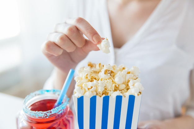 american independence day, celebration, patriotism and holidays concept - close up of woman eating popcorn with drink in glass mason jar at 4th july party