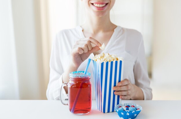 american independence day, celebration, patriotism and holidays concept - close up of woman eating popcorn with drink in glass mason jar and candies at 4th july party