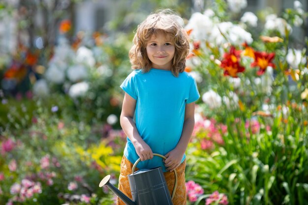 庭の家の園芸で花に水をまくアメリカの子供時代の子供